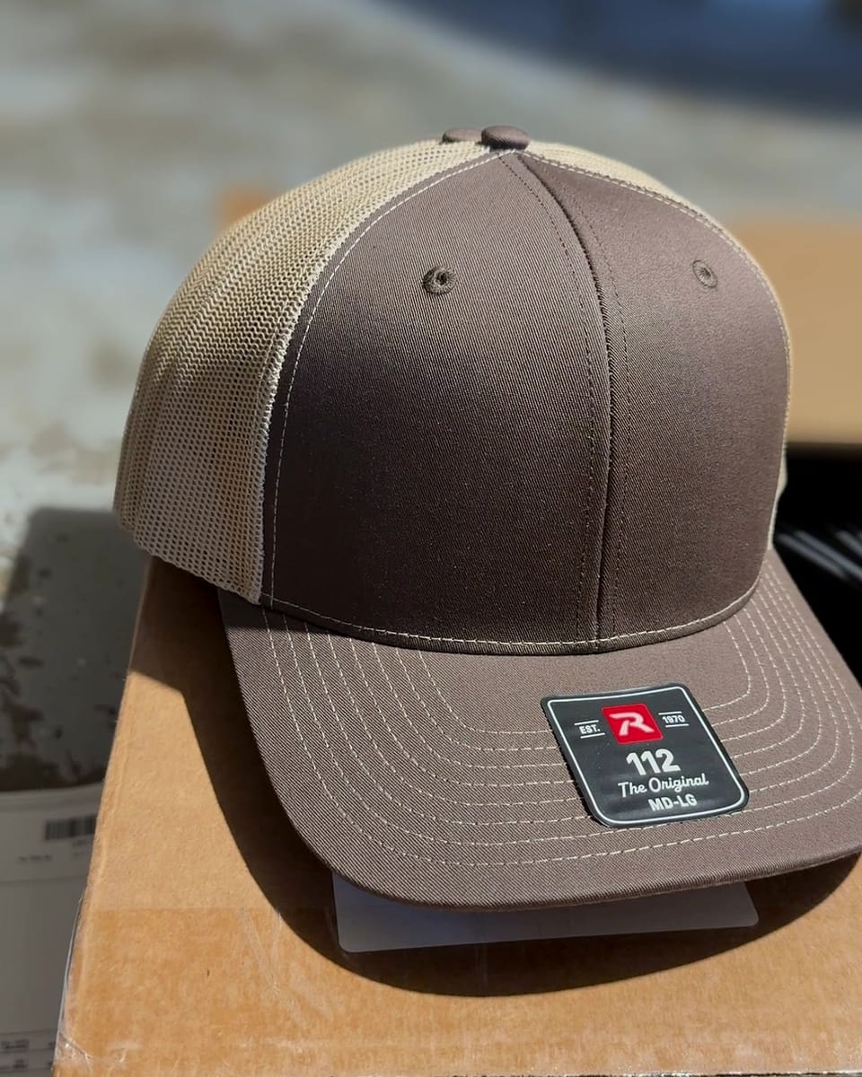 A Brown/Khaki Richardson 112 trucker hat, brown front and khaki mesh, before the patch goes on