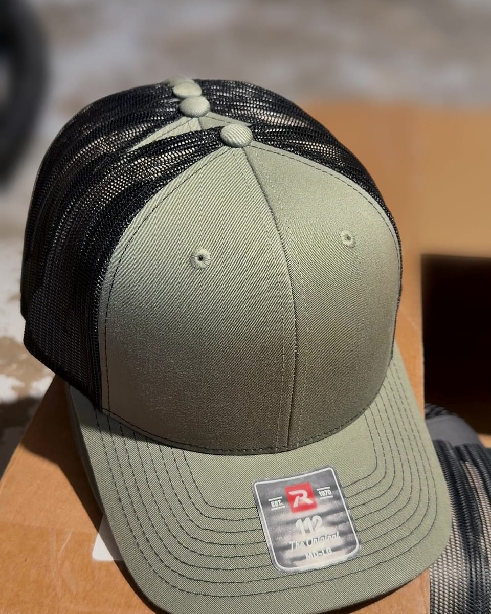 A Loden/Black Richardson 112 trucker hat with its tag still on