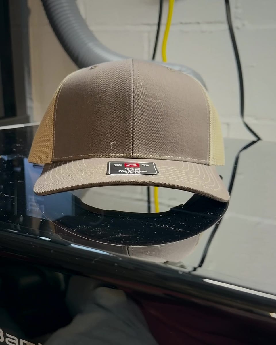 A blank Brown/Khaki Richardson 112 hat sitting on top of the R1